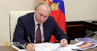 Vladimir Putin signing documents at his desk, with Russian flag in the background and paperwork visible on his desk.