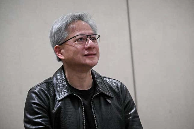 Jensen Huang wearing a black leather jacket and glasses looking forward and smiling