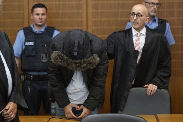 A Syrian doctor, center, accused of torture and war crimes in his Syrian homeland, stands next to his lawyer Oussama Al-Agi, right, in the Higher Regional Court before the verdict is announced in Frankfurt, Germany, Monday, June 16, 2025. (Boris Roessler/dpa via AP)