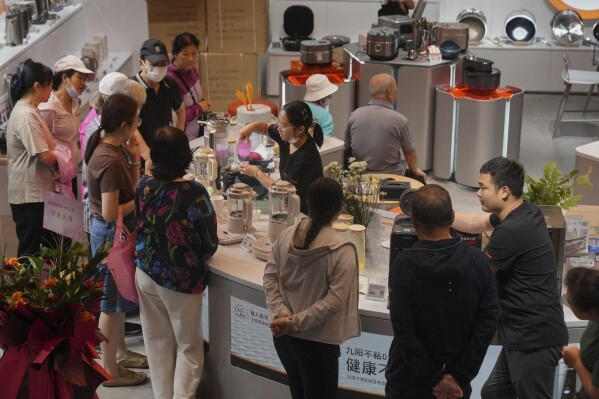 Residents gather to watch a worker demonstrating a juice mixer machine at a newly opened Chinese e-commerce platform JD.com shopping mall in Beijing, Monday, June 16, 2025. (AP Photo/Andy Wong)
