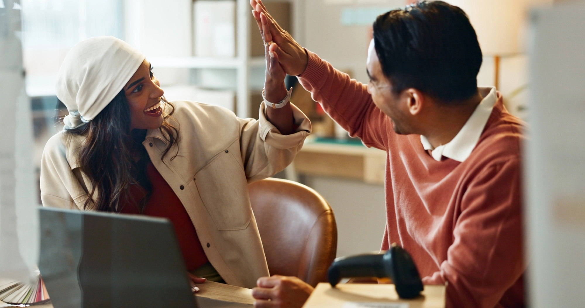 Business partners, high five and laptop for online meeting, startup and funding for costs, goals an