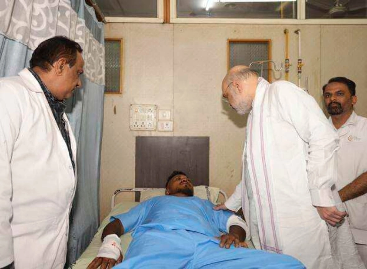 Three men in white jackets surround a man in a hospital bed