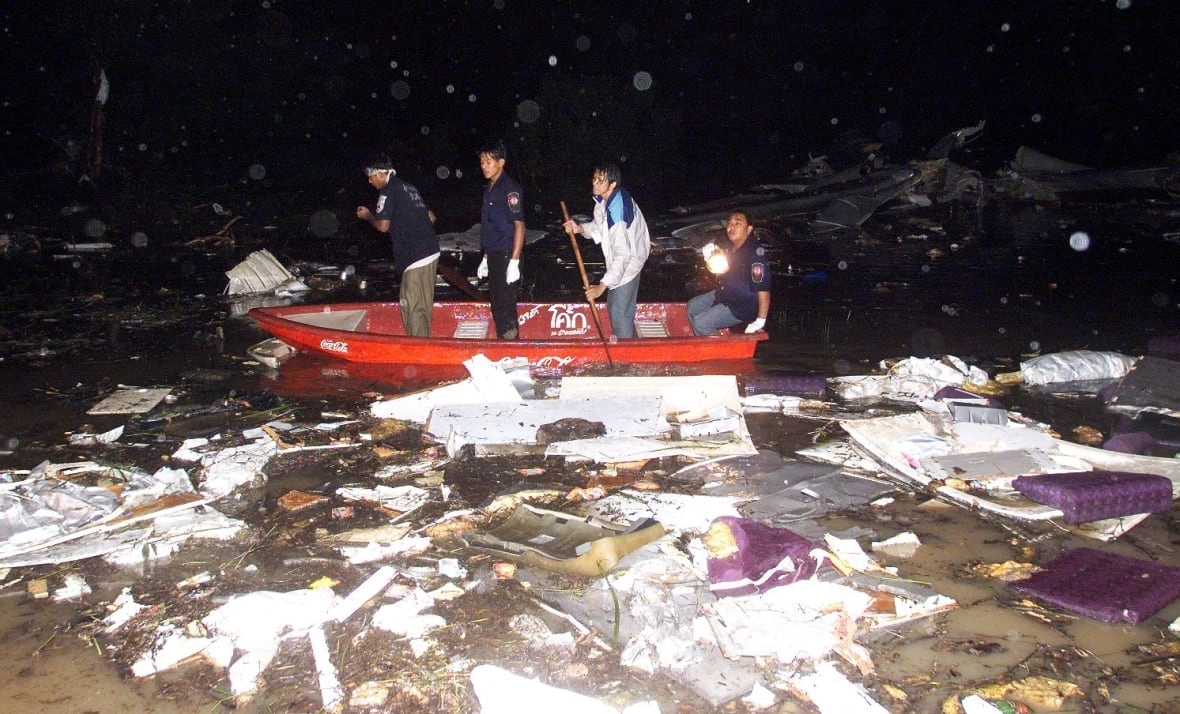 Four men in a rescue boat amid a bunch of floating rubble, at night