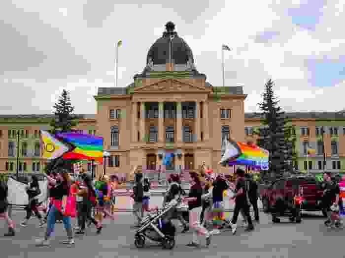 People walk in front of the Saskatchewan Legislative Building during the Queen City Pride Parade