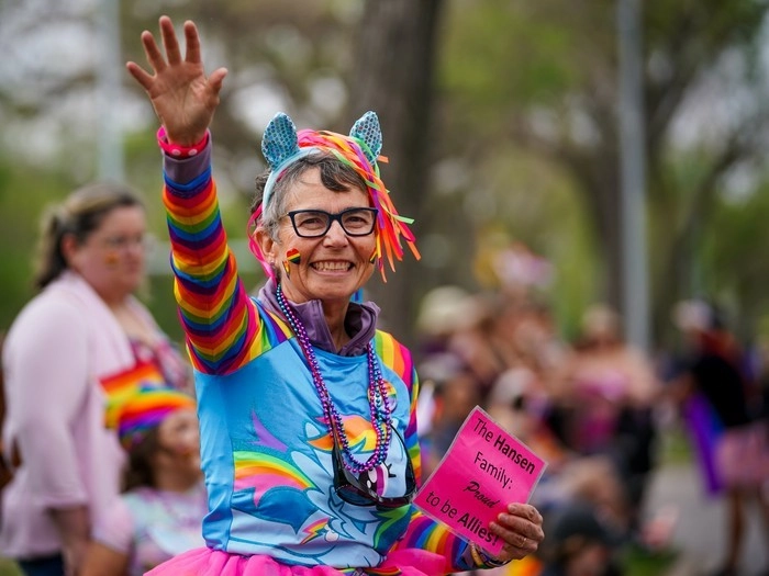 A spectator waves at participants during the Queen City Pride Parade