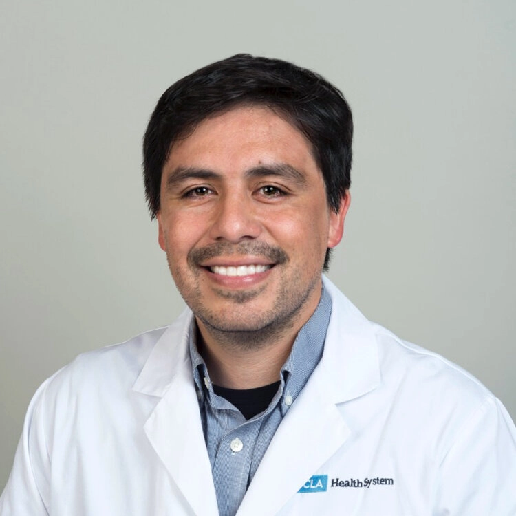 Headshot of a smiling man in a white lab coat.