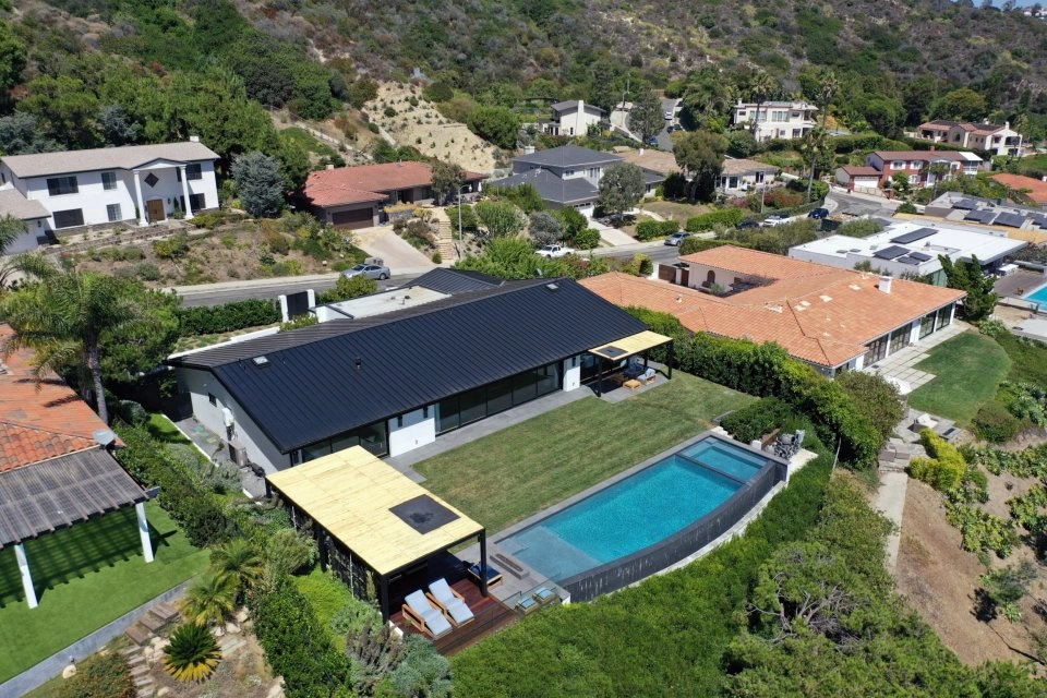 Aerial view of a house with a pool and surrounding homes.
