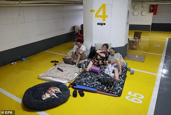 epa12181796 People spend their evening in an underground parking lot amid ongoing Iranian ballistic missile attack threats across the country, in Tel Aviv, Israel, 17 June 2025. Israel's military announced that sirens sounded in various regions across the country after missiles were launched from Iran towards Israel. EPA/ABIR SULTAN