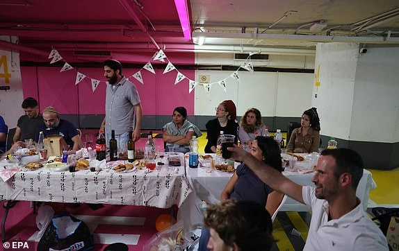 epa12181769 People sing songs after eating dinner at an underground parking lot amid ongoing Iranian ballistic missile attack threats across the country, in Tel Aviv, Israel, 17 June 2025. Israel's military announced that sirens sounded in various regions across the country after missiles were launched from Iran towards Israel. EPA/ABIR SULTAN