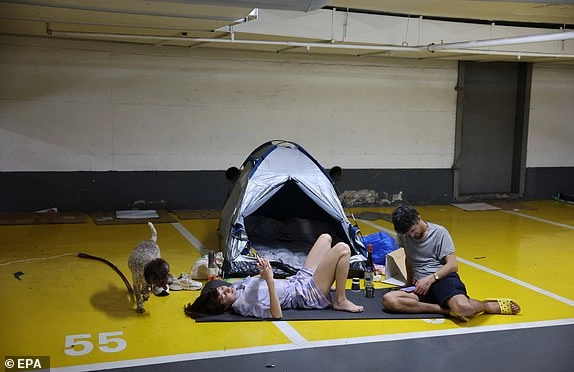 epa12181797 People spend their evening in an underground parking lot amid ongoing Iranian ballistic missile attack threats across the country, in Tel Aviv, Israel, 17 June 2025. Israel's military announced that sirens sounded in various regions across the country after missiles were launched from Iran towards Israel. EPA/ABIR SULTAN