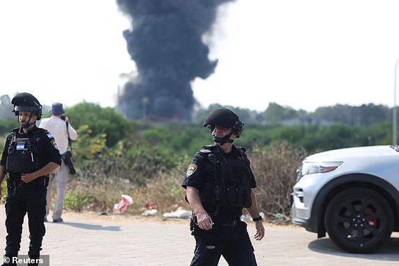 Emergency personnel work, as smoke rises following a missile attack from Iran, in Herzliya, Israel, June 17, 2025. REUTERS/Ronen Zvulun