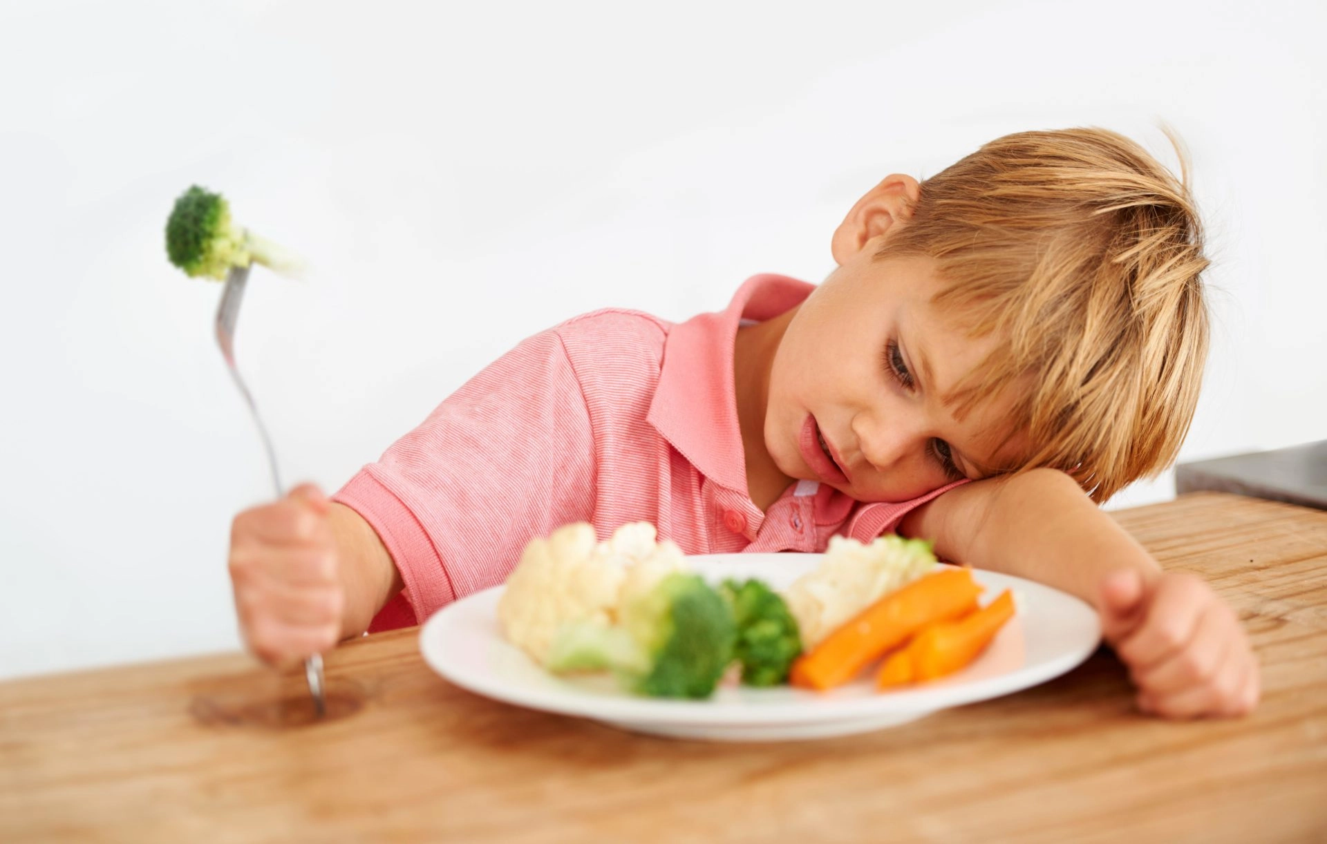 Child eating broccoli at dinner table. Image: Alamy