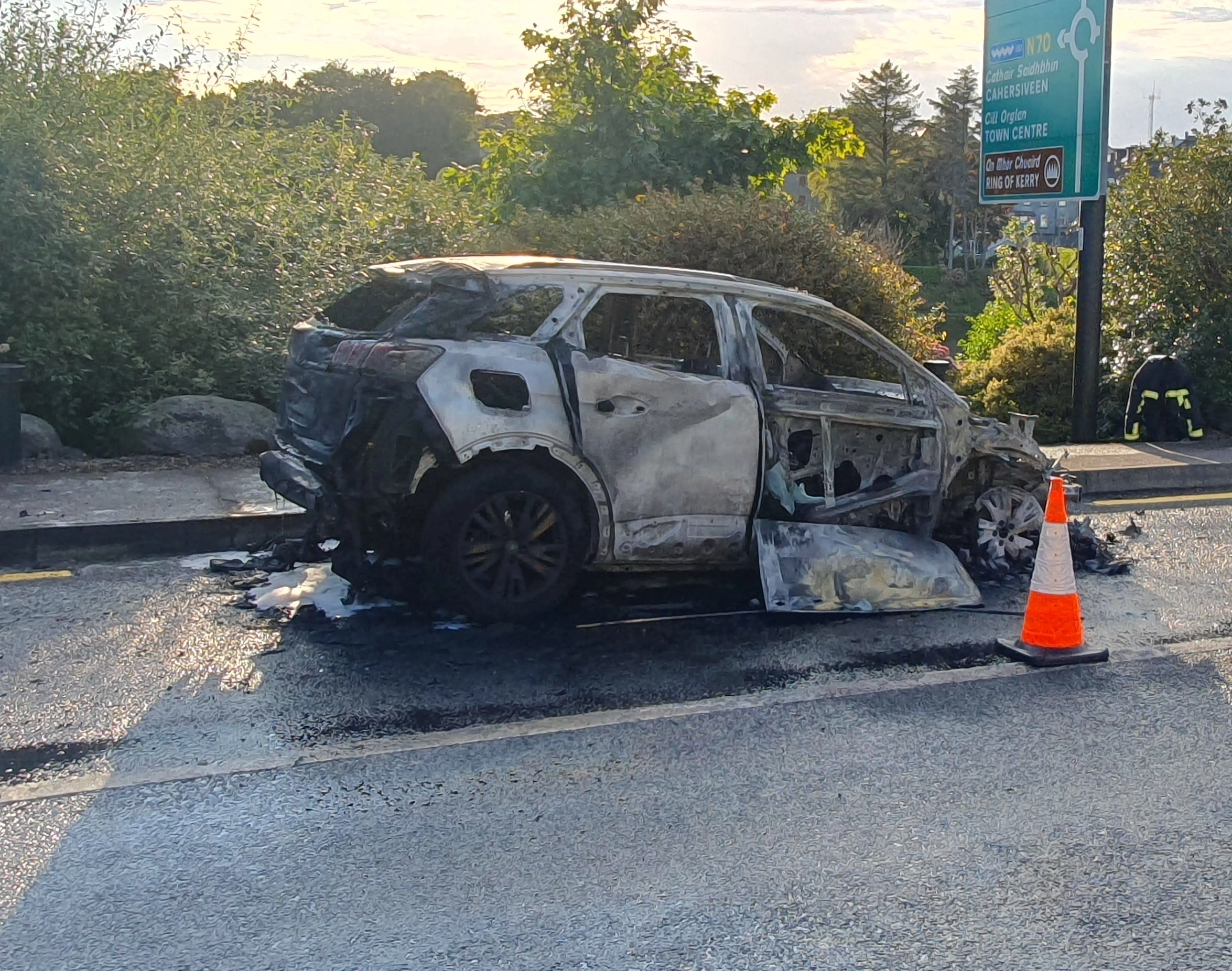 Burned-out Peugeot rental car on the road.