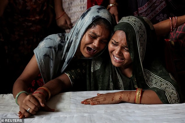 Family members of Akash Patni, who died after an Air India Boeing 787-8 Dreamliner plane crashed during take-off from an airport, mourn as they sit next to his bed in Ahmedabad, India, June 17,2025