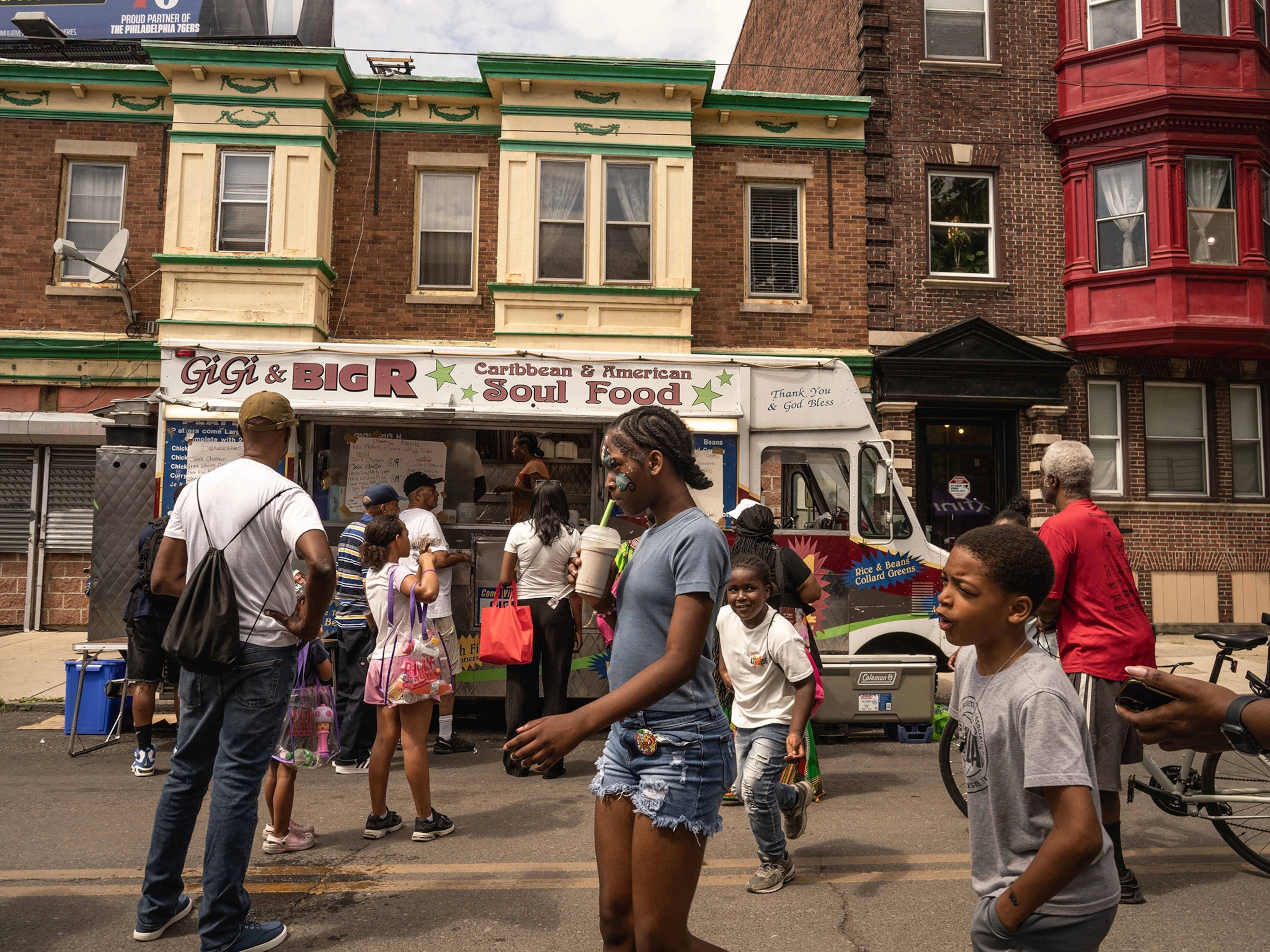 Children and families enjoy local food a white colored food truck is in the background of the image.