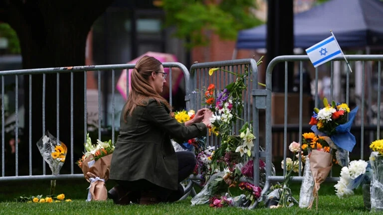 A woman places a bouquet of flowers at a makeshift memorial for victims of an attack outside of the Boulder County, Colo., courthouse Tuesday, June 3, 2025, in Boulder, Colo.