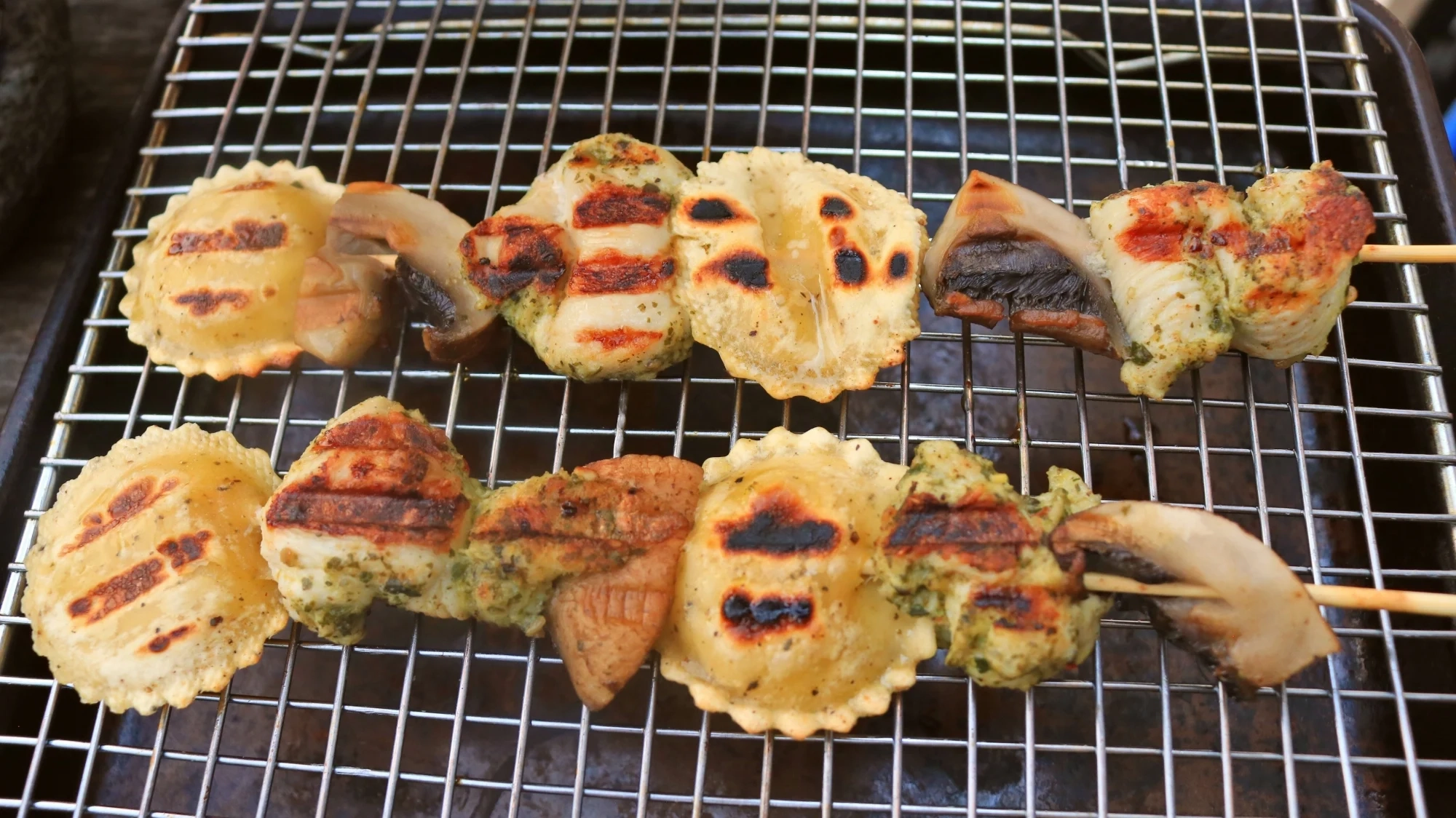 Two skewers with pesto chicken, mushroom, and round ravioli.