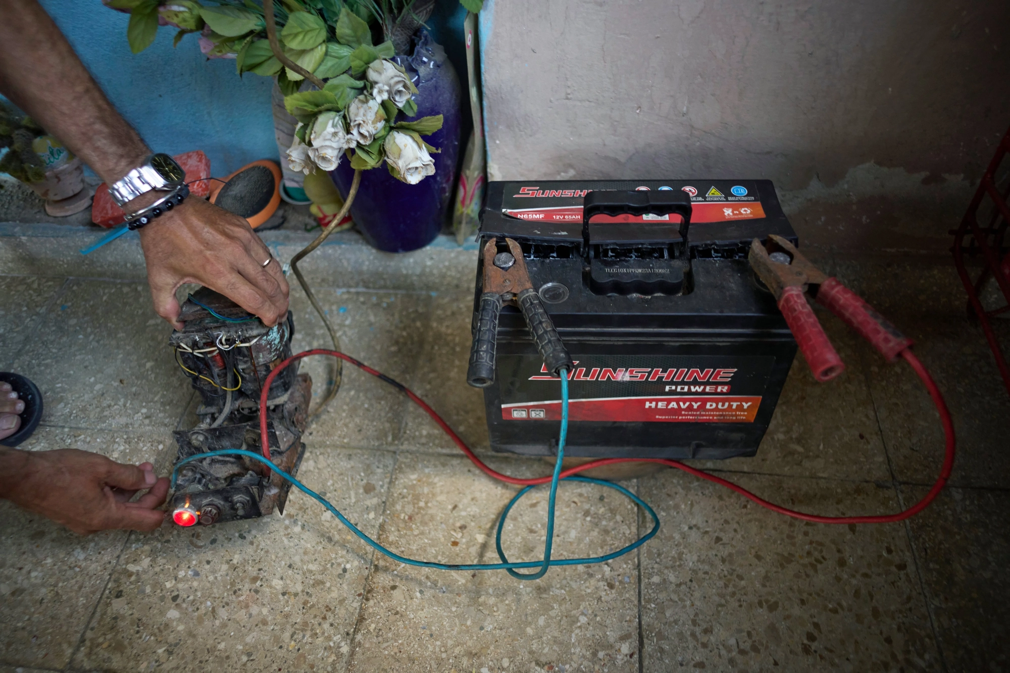 A man uses a transformer from an old television to charge a battery outside his home in Cuba.