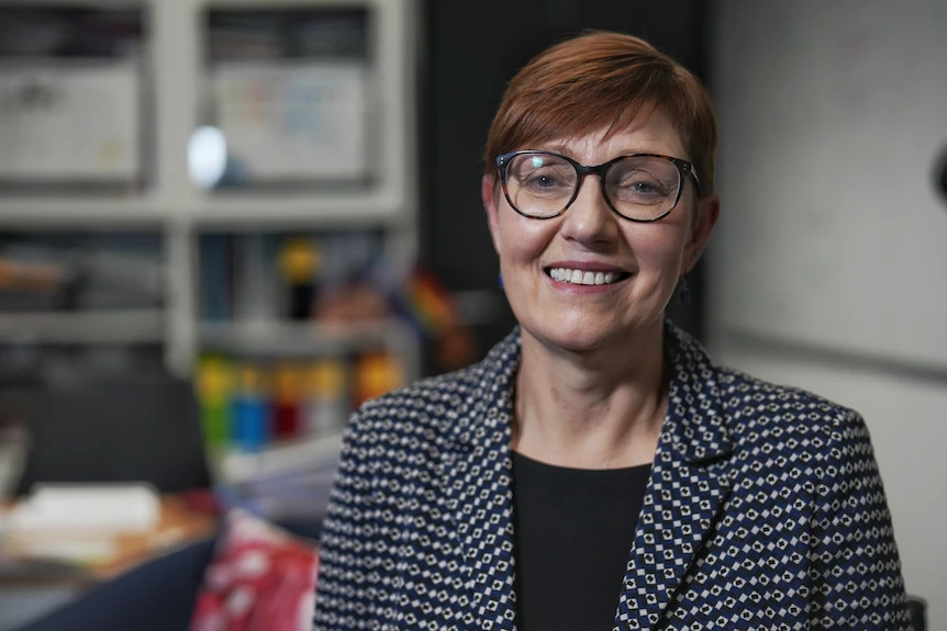 a woman with short red hair and glasses