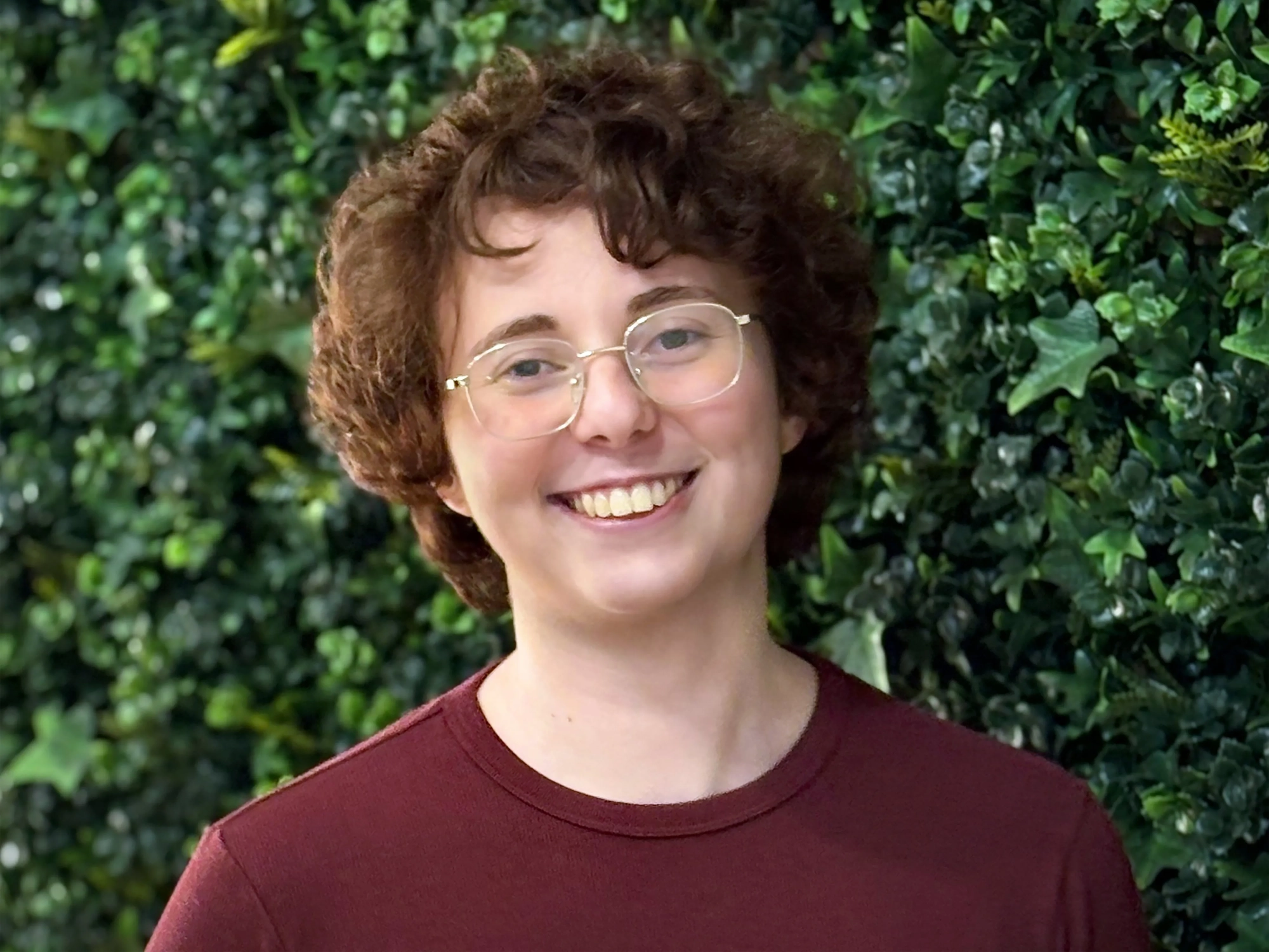 A woman with brown hair who is wearing a maroon t-shirt.
