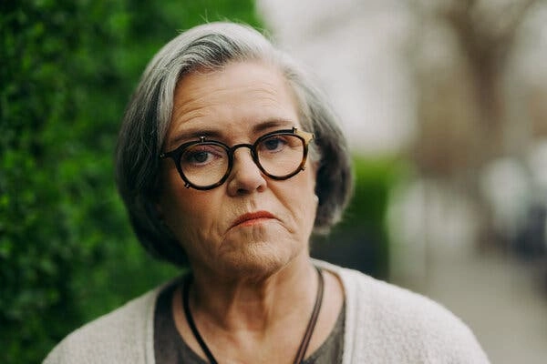 Rosie ODonnell wears glasses and looks into the camera with a neutral expression.