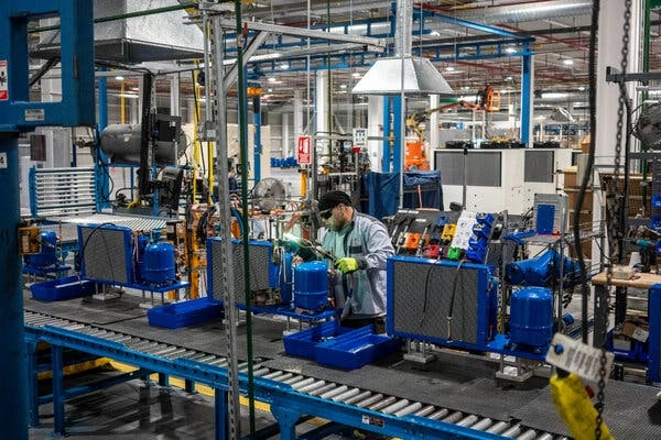 A worker assembles a product in front of an assembly line with blue accents.