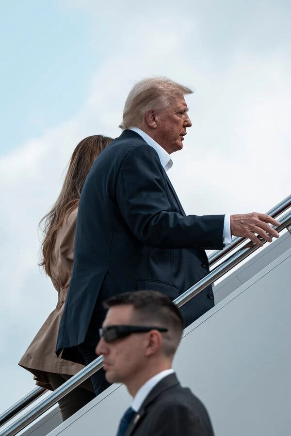 President Trump climbs a stairway onto an airplane.