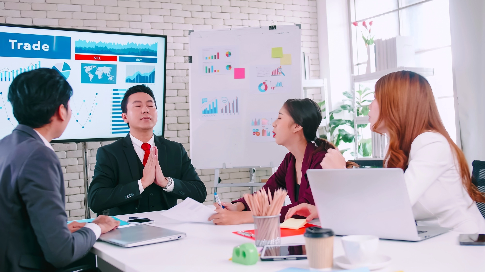 Team leader tries to calm himself while his colleagues are arguing in a meeting.