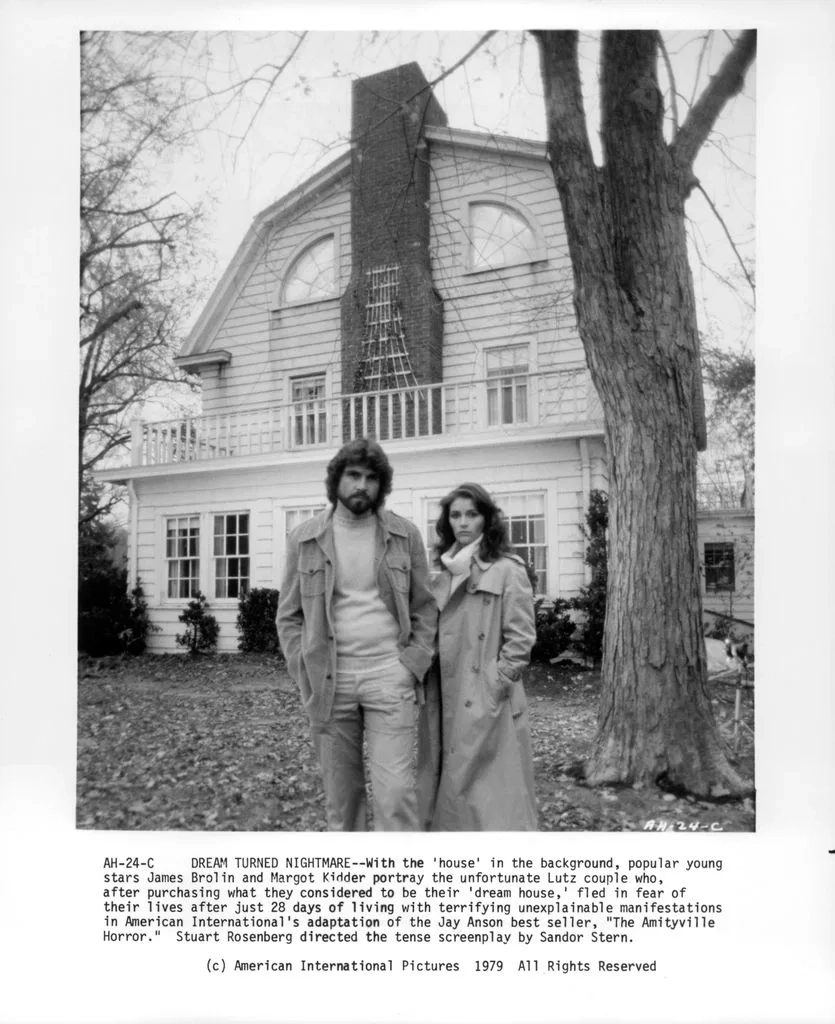 James Brolin and Margot Kidder posing in front of a house in a scene from film 'The Amityville Horror', 1979.
