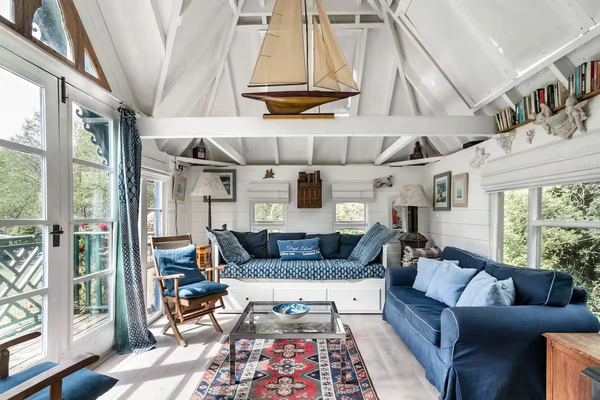 Interior view of a cozy, nautical-themed room with a daybed, sofa, and model sailboat.
