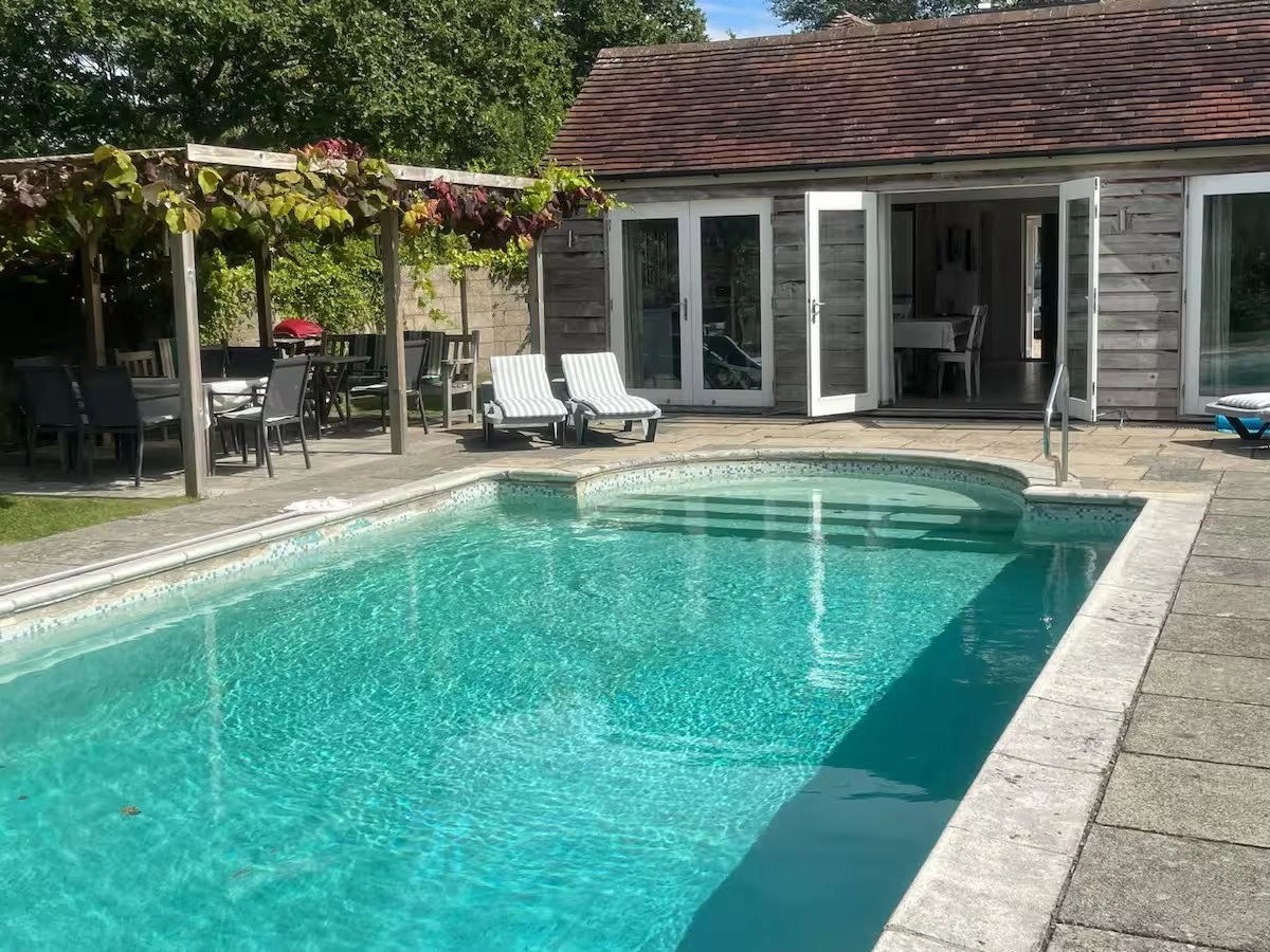 Heated pool and cottage with outdoor dining area.
