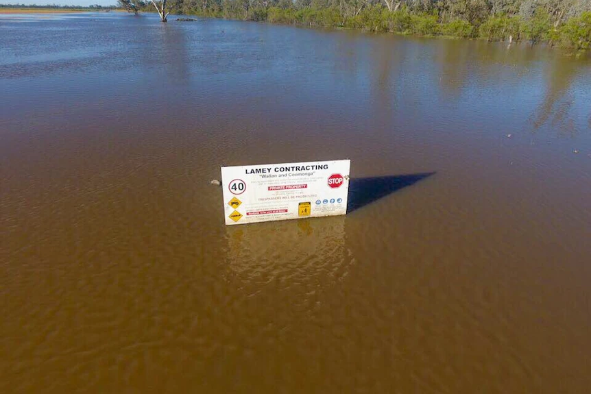Aerial photo of floodwater surrounding a sign that says