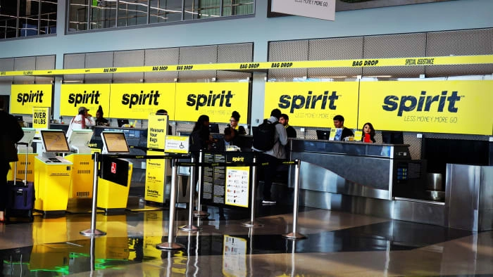People line up at a Spirit Airlines counter. Lead