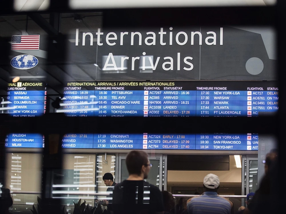 People look at flight information in an airport.