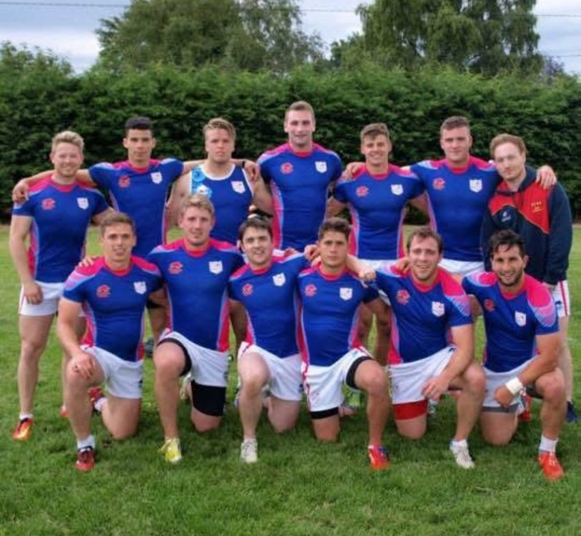 Team photo of rugby players in blue and pink uniforms.