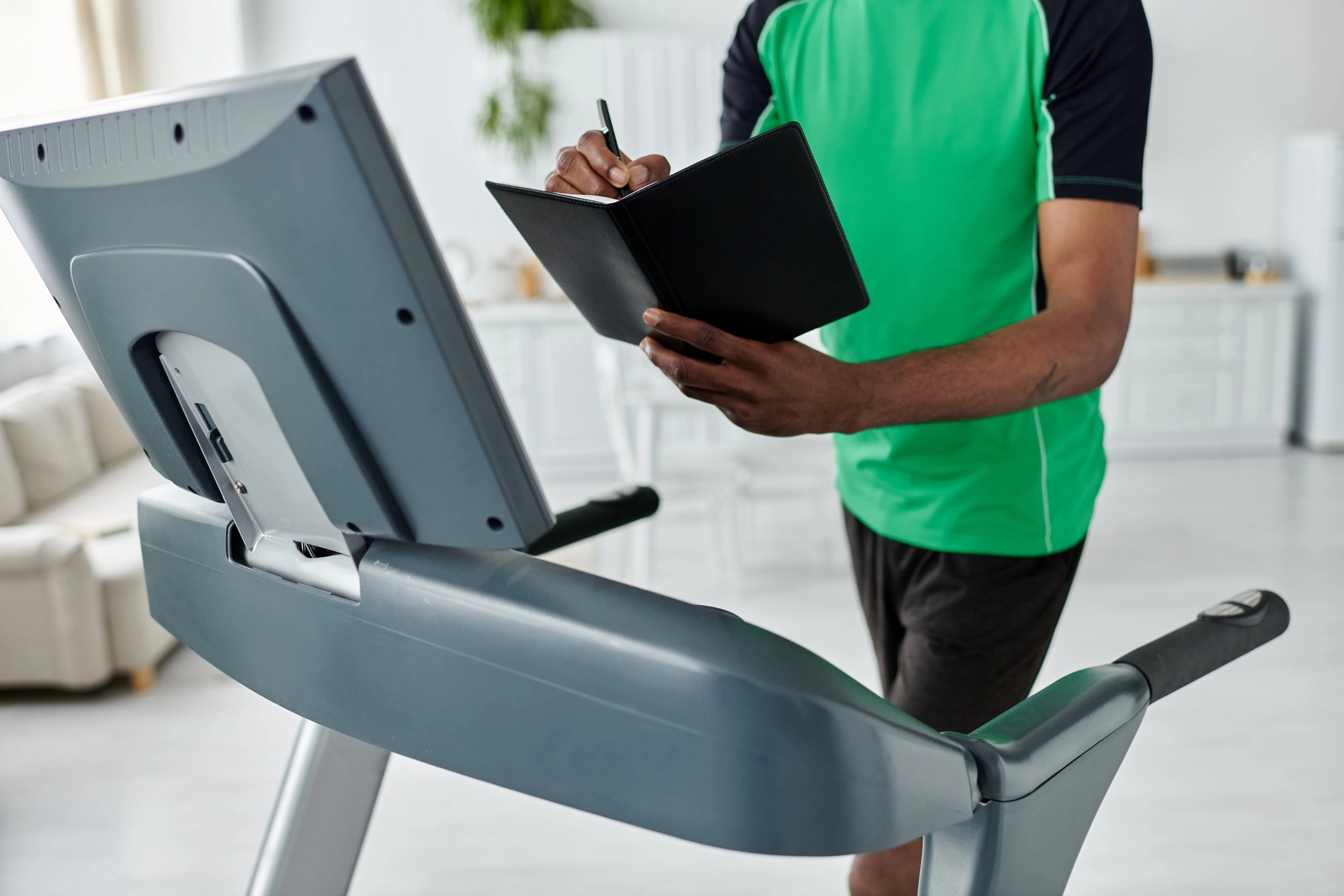 Young man tracks his progress while jogging on a treadmill in a bright modern space