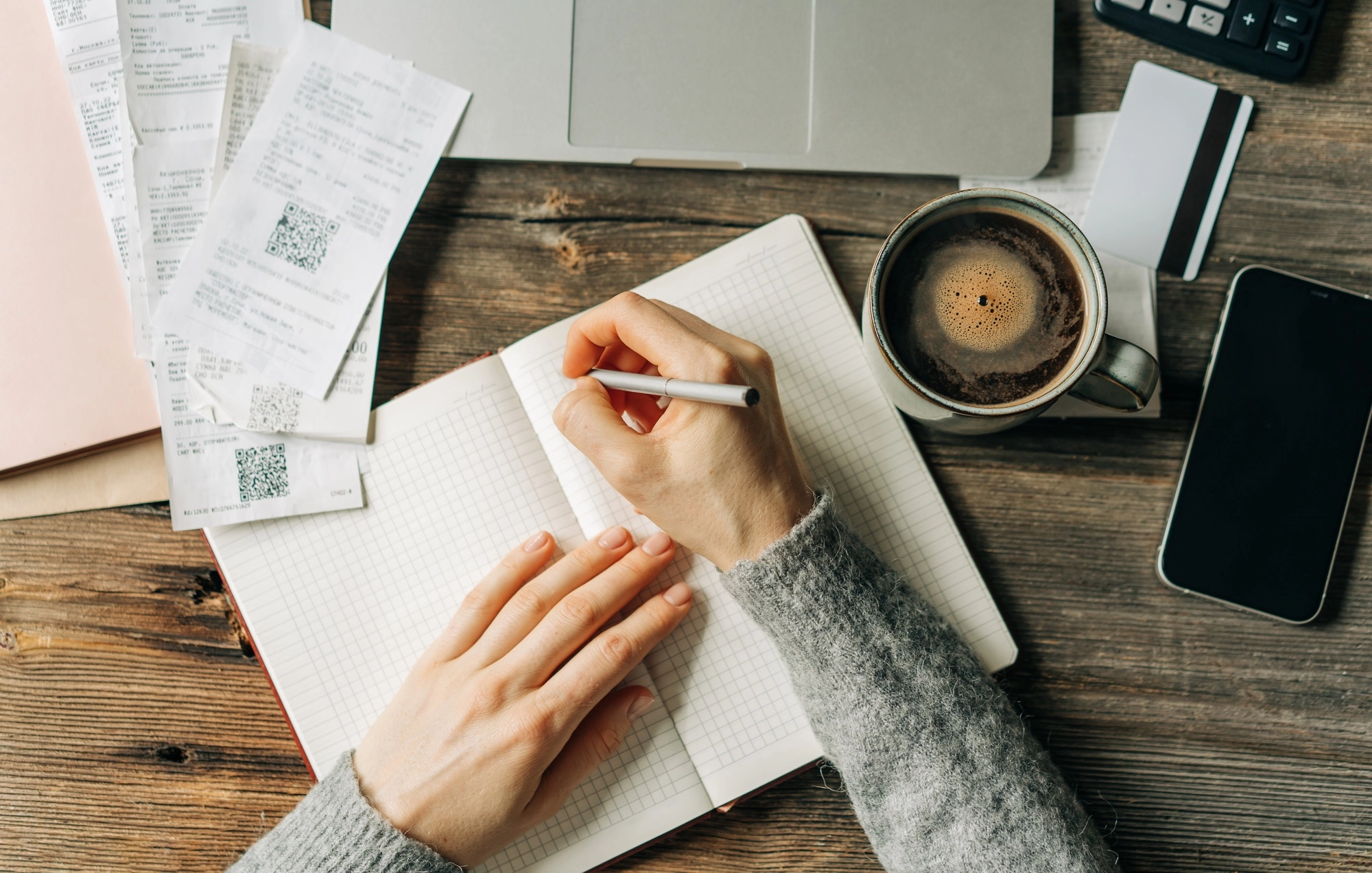 A woman makes an entry in a ledger, the concept of maintaining and planning a personal budget.