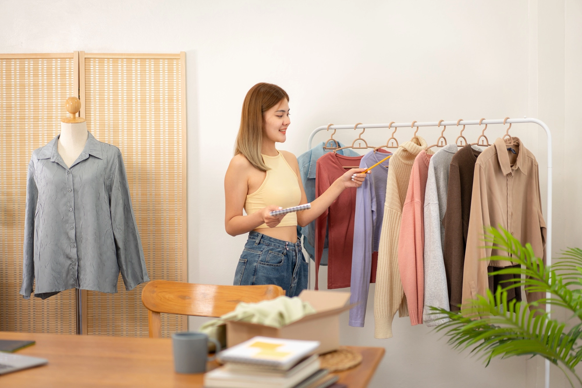 Woman designer entrepreneur checking stock clothes in store and