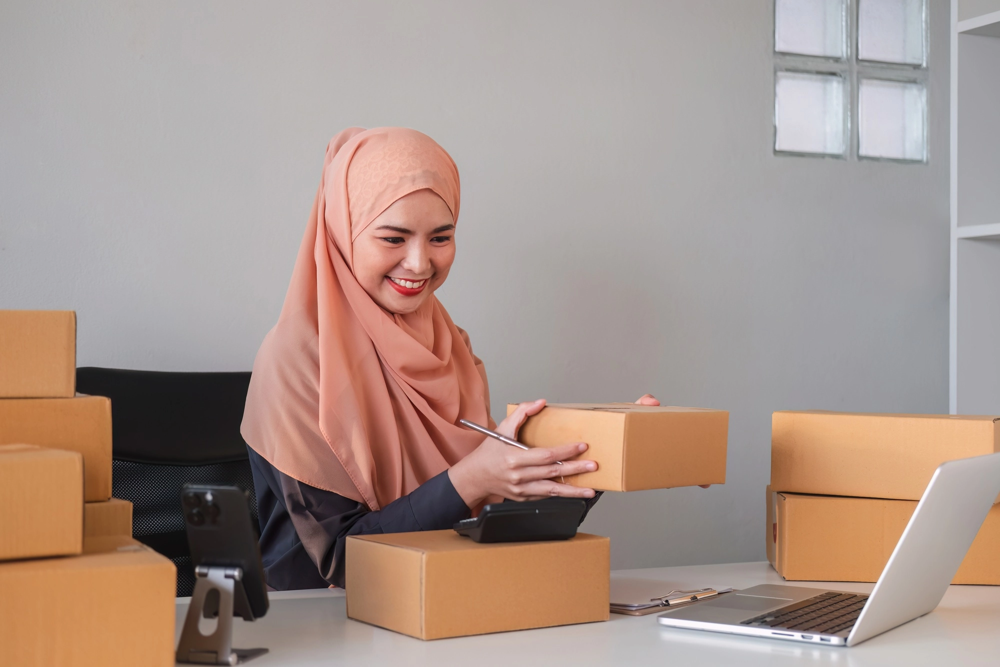 Asian Muslim businesswoman checks stock orders and saves them on her home office laptop. small