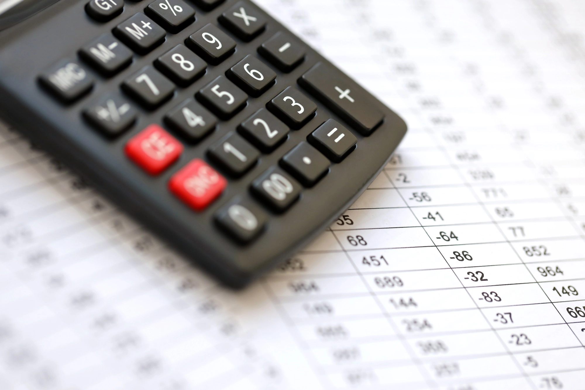 Big black calculator lies on financial statement and balance sheeet on desk of auditor close up
