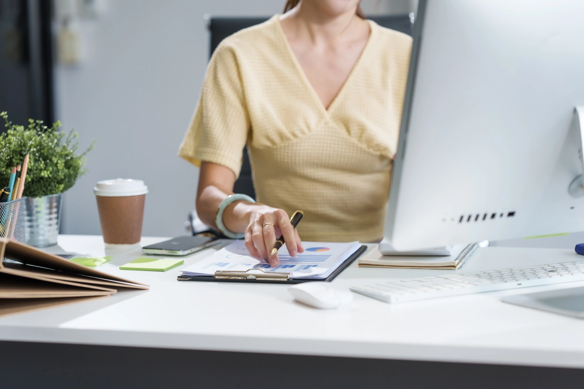 A young Asian woman sits at a desk, attentively analyzing graphs and financial data.She is focused