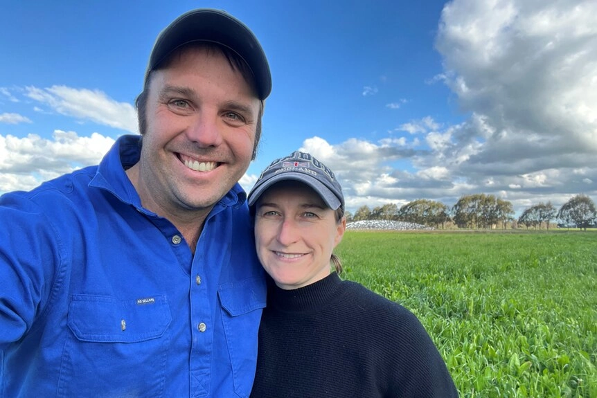 A middle-aged man and woman stand together outside in a cropped paddock