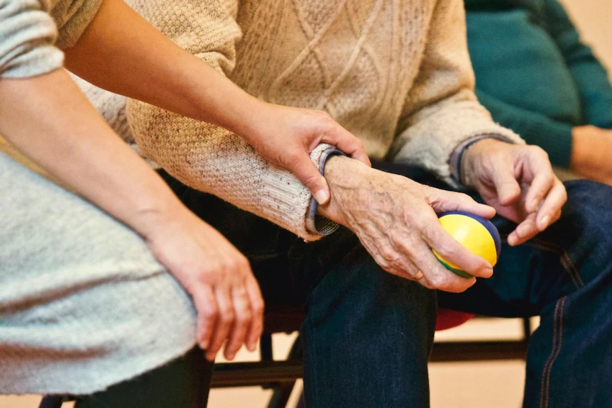 Closeup of a hand on a senior citizen's holding a colourful ball