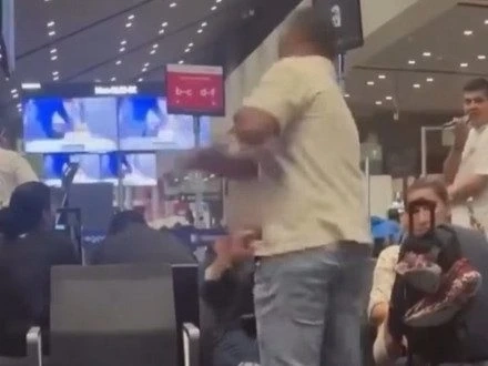 Screenshot of man slapping woman after she refused to give up her seat.