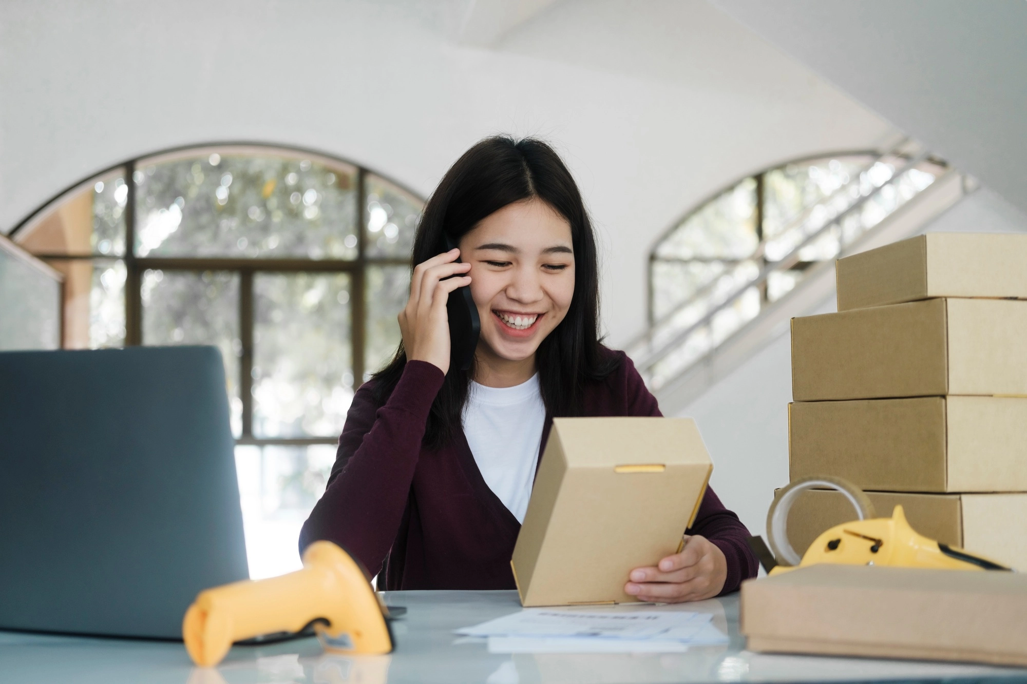 Female online business, store owner talking to customer using smartphone.