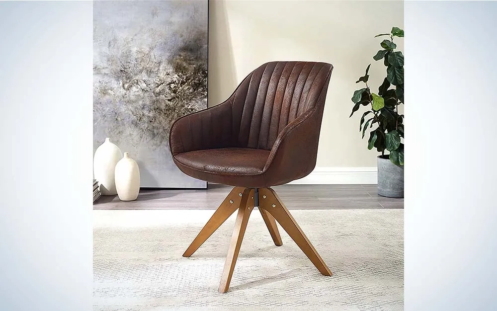 The brown upholstered Art Leon Mid-Century Modern Accent Chair is on a cram-colored rug with a plant, vases, and a gray abstract painting in the background.