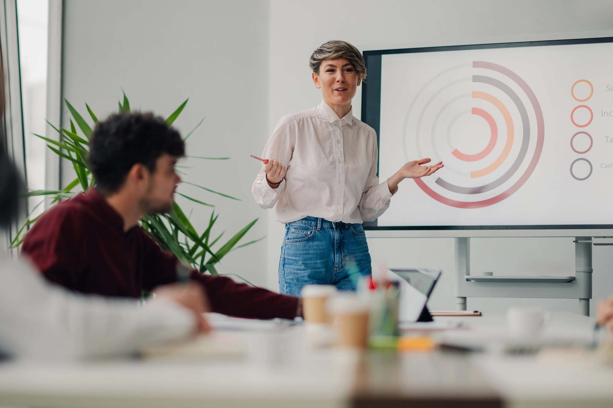 Young businesswoman presenting marketing data on a whiteboard during a meeting