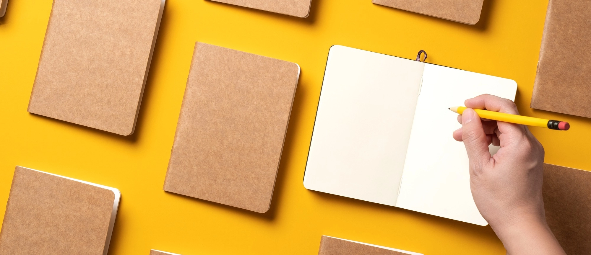 .top view of hand writing on open notebook align with kraft paper book