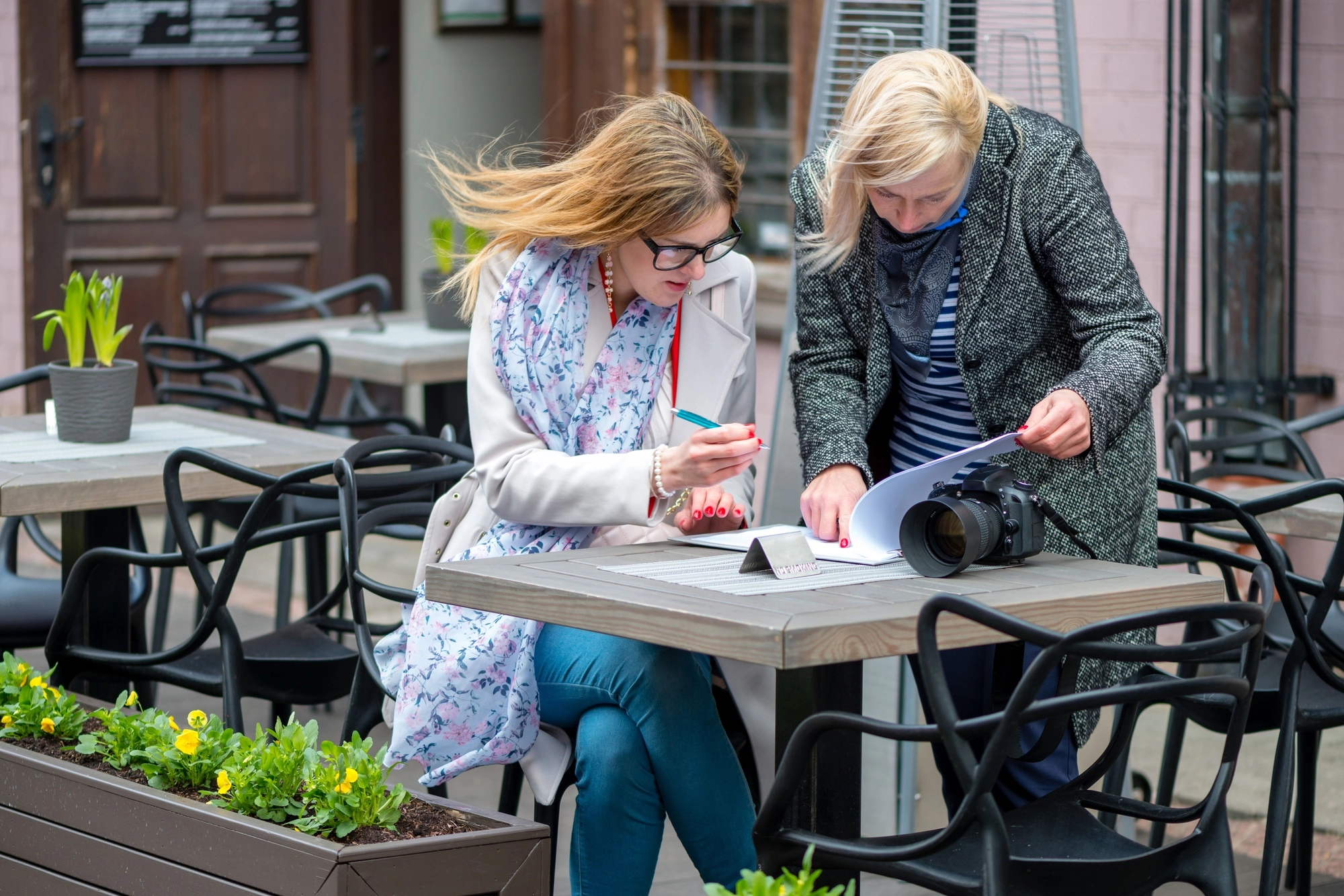 Two business women in an outdoor cafe closed the deal and sign the documents