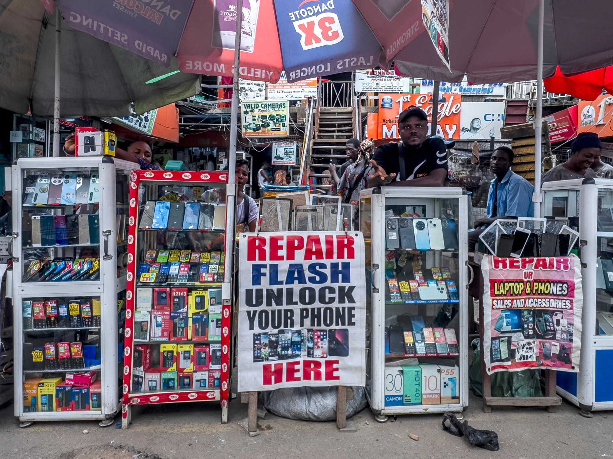 Photo of a row of color display cases holding cellphones, with signs offering phone and laptop repair.